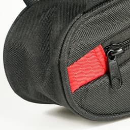 A black bike triangle bag features a red zipper tab and textured fabric, with a logo visible on the side.