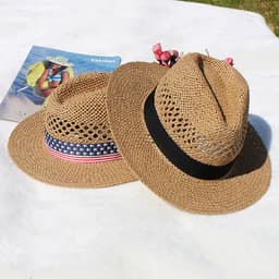 Two custom straw hats in brown, one with a red, white, and blue band, placed on a light surface with a magazine nearby.