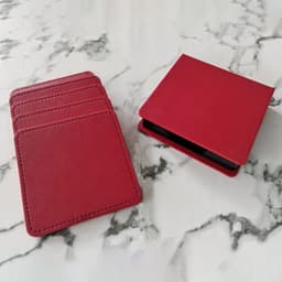 Four red PU leather coasters stacked beside a matching storage case on a marble surface.