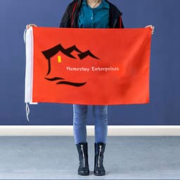 A large red hand waving flag held by a person, featuring a logo and design with a mountain and house.