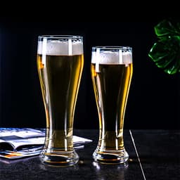 Two clear glass pilsner beer glasses are filled with golden beer and topped with frothy white foam.