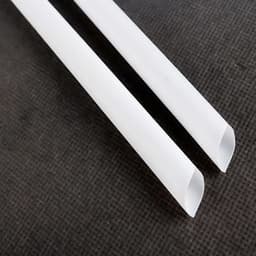 Two white biodegradable straws positioned side by side on a textured dark background.