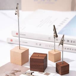 A wooden alligator clip menu stand with metal clips, featuring light and dark wooden bases.