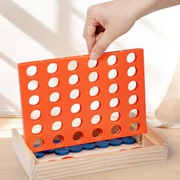 A hand placing a disc in an orange Four In A Row game with blue discs visible in the wooden base.