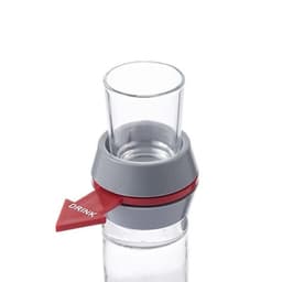 A glass shot glass with a grey and red spinner attached, featuring a directional arrow.