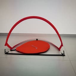 A pop-up football goal in vibrant red, featuring a curved frame and flat base, showcasing an organised design.