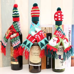 A drink bottle dressed in a red and green knitted hat and scarf, featuring festive patterns and colours.