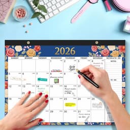 A monthly planning pad for 2026 with floral designs in blue and cream, featuring a hand writing on it.