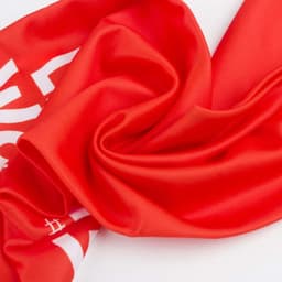 A red custom sports fan scarf with a smooth texture and a logo or branding present.