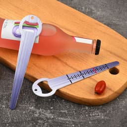 A drink bottle opener and seed depth tool in purple, featuring measurement markings, placed on a wooden cutting board.