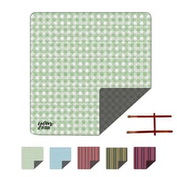 A green and white patterned picnic blanket with a grey underside and brown leather straps for easy carrying.