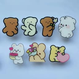 A collection of cute cartoon animal magnets, featuring bears in various poses and a cat holding flowers, in pastel colours.