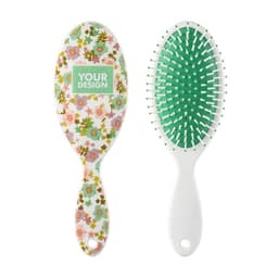A paddle hair brush featuring a floral design on one side and a green bristle pad on the other. It has a white handle.