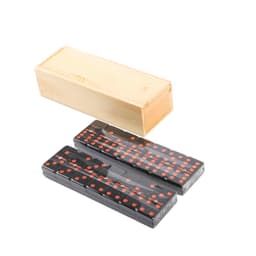 A wooden box containing a set of black dominoes with red dots.