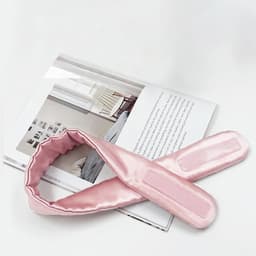 A pink silk headband with a smooth texture, displayed beside a magazine on a white surface.