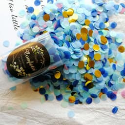 A clear tube filled with blue and gold confetti, surrounded by scattered pieces of the same confetti on a white background.