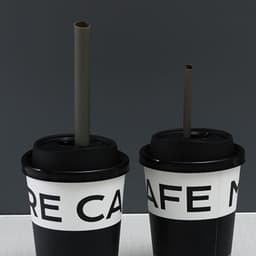 Two biodegradable disposable drinking straws in brown, placed in black cups with white text.