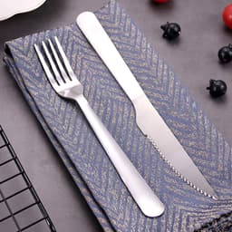 A stainless steel cutlery set featuring a fork and a knife, placed on a textured blue napkin.