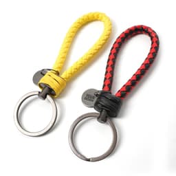 A unisex braided leather rope keychain in yellow and red, featuring a metal keyring and a logo tag.