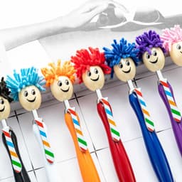 A selection of colourful ballpoint pens with mop head tops and smiling faces, featuring various hair colours and ties.