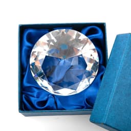 A diamond-shaped paperweight with a clear, faceted design inside a blue presentation box.