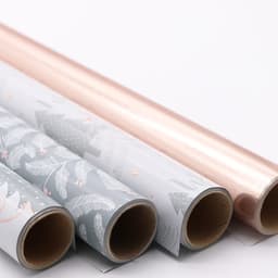 Four rolls of customised gift wrapping paper in grey with patterns and shiny rose gold, featuring a branding logo.