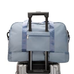 A large capacity travel duffel bag in blue, featuring a front pocket and placed on a wheeled suitcase.