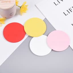 A set of four round coasters in red, yellow, pink, and white, featuring a smooth surface and a branding logo.