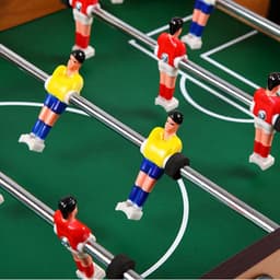 A tabletop football game featuring red and yellow player figures on a green pitch with silver rods.