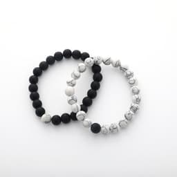 Two bracelets, one black lava stone and one white marbled stone, displayed together on a white background.