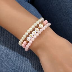 A set of three stretch plastic bracelets featuring pink and white beads, with one bracelet displaying the word "LOVE."