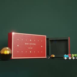 A red custom gift box with a greeting card set, featuring gold detailing and decorative mini toys on a green background.