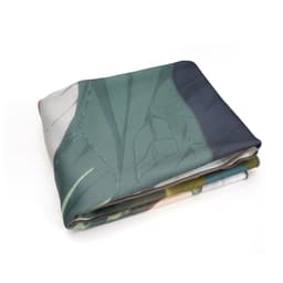 A folded coral fleece throw blanket featuring a printed design in green and other soft colours. It includes a logo.