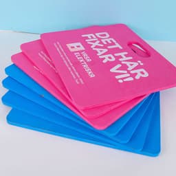A stack of seat cushions in pink and blue colours, featuring a handle for easy carrying.