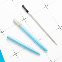 A set of metal ballpoint pens in blue with a black tip, displayed on a white grid background.