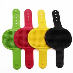 Four grooming brushes in green, red, yellow, and black, featuring textured surfaces and flexible handles.