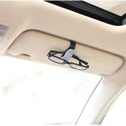 A black car glasses clip mounted on a vehicle's overhead visor, holding a pair of glasses.