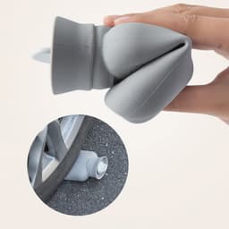 A grey silicone hot water bottle featuring a knitted sleeve, held in a hand with a close-up showing the spout.
