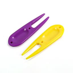 A golf divot fork in purple and yellow, featuring two pointed prongs and a rounded body with a hole.