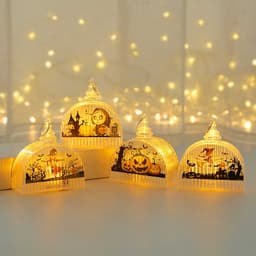 Four decorative pumpkin light lamps in orange and clear designs, featuring Halloween motifs against a softly lit background.