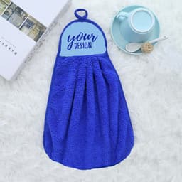 A blue coral velvet hand dry towel with a hanging loop and a blank area for custom design, placed beside a cup and plate.
