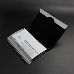 A stainless steel card holder with a sleek black interior, featuring a logo on the exterior.