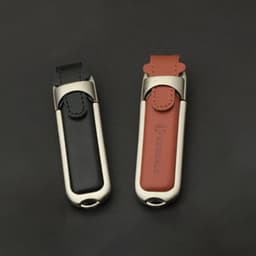A leather USB flash drive in black and brown, featuring a sleek metallic casing and a logo.