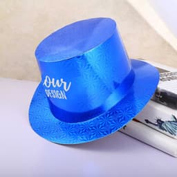 A blue paper top hat with a shiny surface and a decorative pattern, resting on books. It features a branding element.