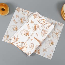Custom wrapping paper featuring brown illustrations of desserts and flowers on a white background, with some baked goods nearby.
