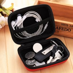 A red EVA hard carry case containing earphones, coins, keys, and a USB drive, with a mesh pocket.
