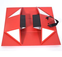 A red collapsible wine box with black handles and triangular flaps, featuring a logo.