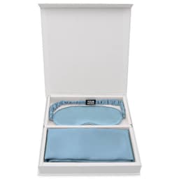 A boxed set featuring a light blue silk eye mask and a matching silk pillowcase. The box has a logo.
