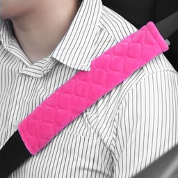 A pink car seat belt cover pad with a quilted design attached to a seat belt, resting on a person's shirt.
