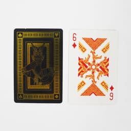 Two playing cards displayed: one black with gold design and the other in white and red featuring intricate patterns and numbers.